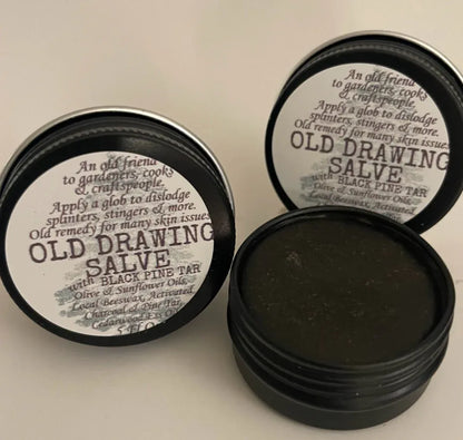 Multiple small metal tins with black lids, each labeled 'OLD DRAWING SALVE with Black Pine Tar'.