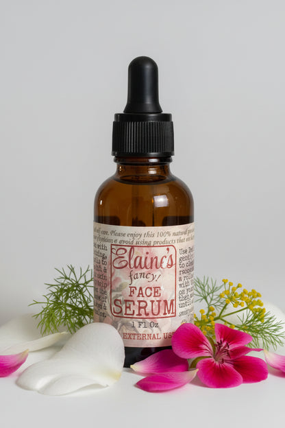 Brown glass bottle with dropper labeled 'Elaine's Fancy Face Serum' on a light gray background