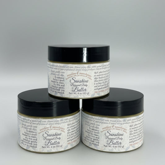 Three jars of Sunshine Baby Body Butter on a gray background
